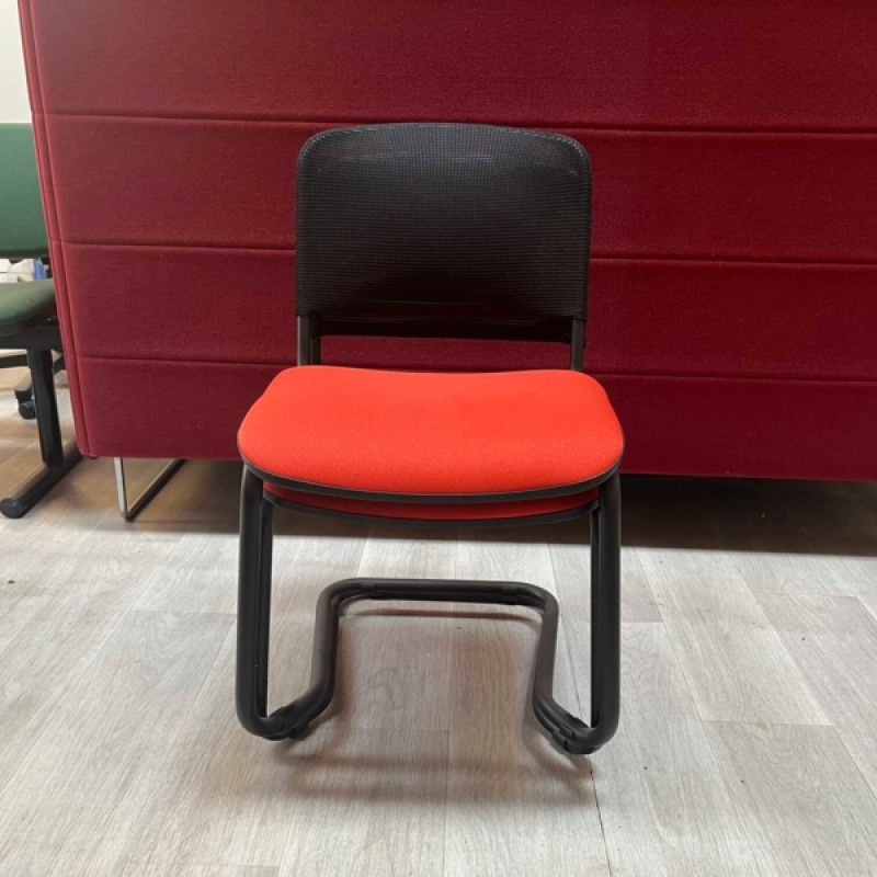 Chaise de bureau simple et fonctionnelle avec assise rouge et dossier en maille noire, parfaite pour un poste de travail compact et polyvalent.
