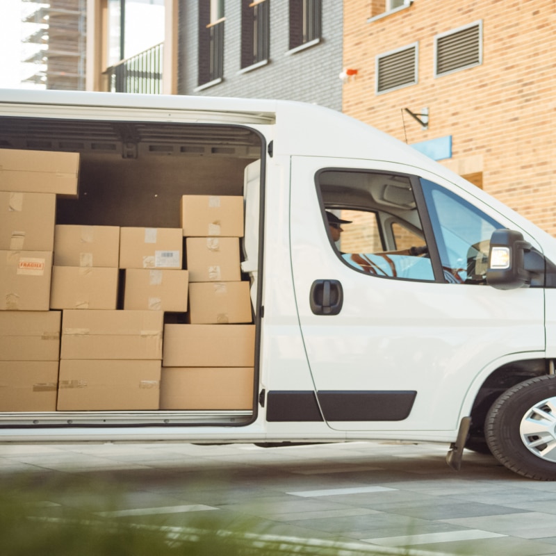 Véhicule utilitaire pour la livraison de mobilier de bureau, rempli de cartons destinés à aménager des espaces de travail professionnels.